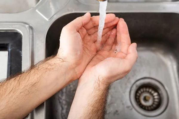 Man washing hands with antibacterial soap and water in metal sink for corona virus prevention. Hand hygiene, health care, medical concept. Hand skin disinfection protect from Coronavirus covid 19.