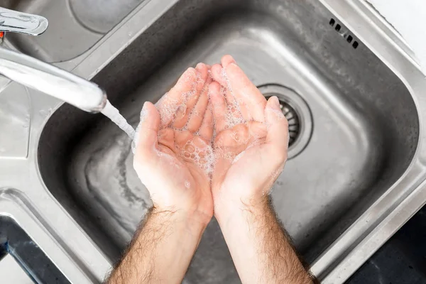 Man washing hands with antibacterial soap and water in metal sink for corona virus prevention. Hand hygiene, health care, medical concept. Hand skin disinfection protect from Coronavirus covid 19.