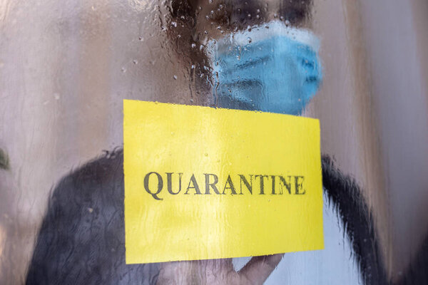 Одинокий человек в карантине с ковидом-19 в изоляции дома. Желтый предупреждающий знак с текстовым карантином в окне. Предотвращение пандемии коронавируса. Мужчина в защитной медицинской маске дома. Концепция медицины
.