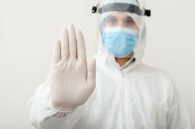 Koruyucu giysi giyen ve yüz maskesi takan bir doktor beyaz arka planda Covid-19 salgınını durdurduğunu gösteriyor. Sağlık hizmeti kavramı covid coronavirüs karantinası