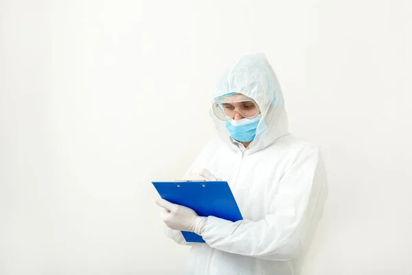 Coronavirus, covid-19 doctor appointment. Doctor or scientist in protective medical suit, biological hazard, face mask doctor writes on tablet on white background. Medical healthcare concept.