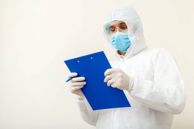 Coronavirus, covid-19 doktor randevusu. Koruyucu giysili doktor, biyolojik tehlike, yüz maskesi doktoru tablete yazıyor. Tıbbi sağlık hizmeti kavramı