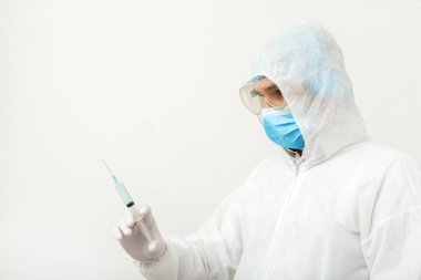 Coronavirus, covid-19 aşısı. Koruyucu tıbbi giysi giyen doktor bilim adamı, biyolojik tehlike, yüz maskesi şırıngada aşı tutuyor. Aşı tıbbi sağlık hizmetleri pandemik önleme kavramı