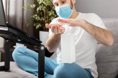 Erkeklerin ellerini temizlemek için dezenfektan jeli. Coronavirus Covid 19 koruma, el hijyeni. Yüz cerrahisi maskeli serbest çalışan. Ev karantinasında uzaktan çalışma. Sağlık hizmetleri için deri dezenfektanı.