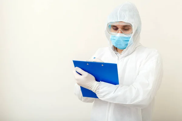 Coronavirus, covid-19 doctor appointment. Doctor in protective medical suit, biological hazard, face mask doctor writes on tablet. Medical healthcare concept