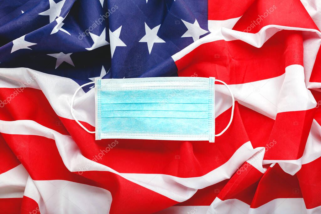 Covid-19 Coronavirus in USA. Protective surgical face mask on American national flag. U.S. flag and hygienic mask as symbol of protection prevention viral infection coronavirus. Medicine health care.