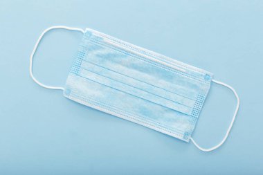 Tıbbi maske, mavi arka planda tıbbi koruyucu maske. Tek kullanımlık yüz maskesi ağız ve burnu kapatır. Sağlık ve Tıp Konsepti.