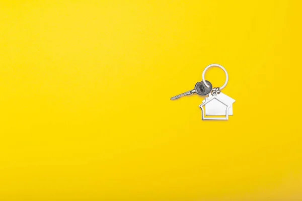 Chaves da casa com bugiganga no fundo de cor, vista superior com espaço de cópia. Chave da casa no fundo amarelo. Estilo de leigos plano mínimo com lugar para texto . — Fotografia de Stock