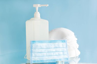 Tıbbi yüz maskeleri, cerrahi koruyucu yüz maskesi N95 ve mavi arka plandaki elleri sterilize etmek için bir şişe alkol jeli. Coronavirus covid 19 virüs önleme, el hijyeni sağlık hizmetleri tıbbi konsepti