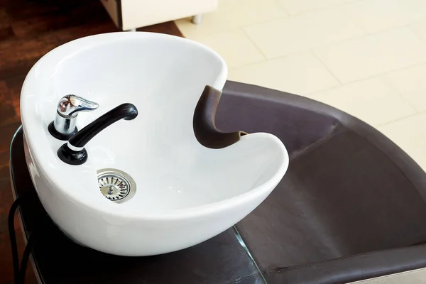 Wash sink for washing hair in beauty salon Barber shop.Hairdresser stylist work space.Hairdressing bowl,hair washer equipment for head washing.Hair care spa procedures.Water tap beauty Salon Interior.
