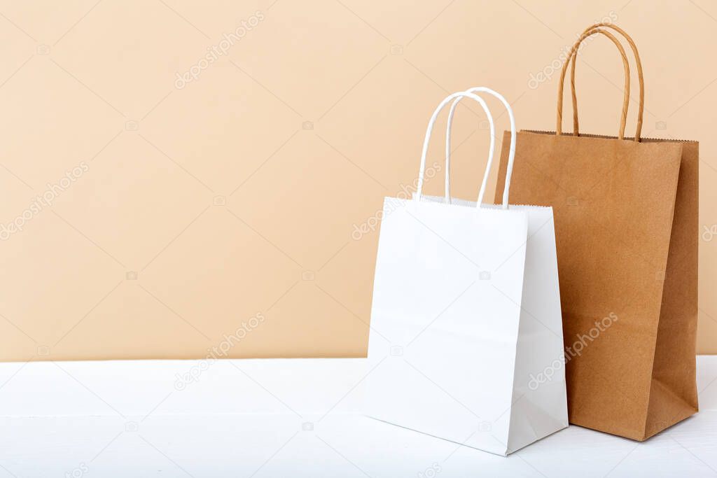 White brown craft paper bags. Shopping Mockup bags paper packages on white table beige light background with copy space. Shopping, sale, Food delivery service. Copy space.