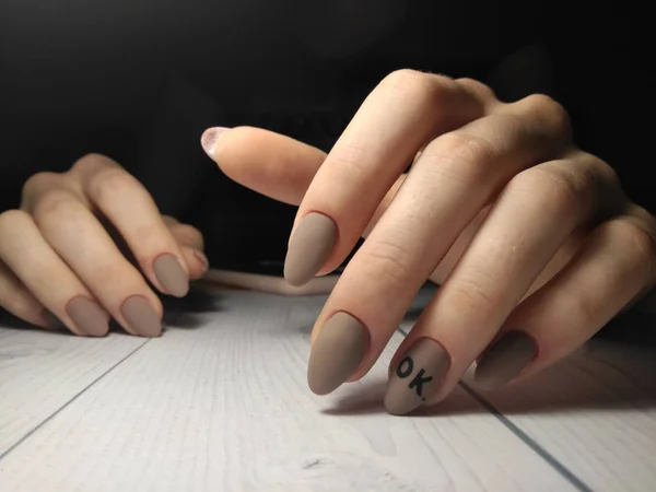 ジェルポリッシュで女性用ペン 黒の碑文のデザインの茶色の爪カバー 碑文マットマニキュアでOk マニキュア師の仕事 — ストック写真