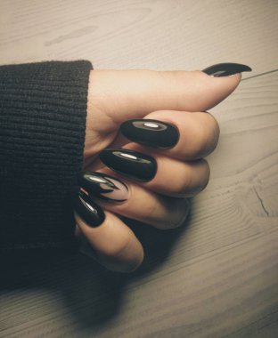 Gotik siyah manikür tarzı. Siyah parlak kaplamalı jel cilası ve ahşap masa üzerinde siyah alev tasarımı..