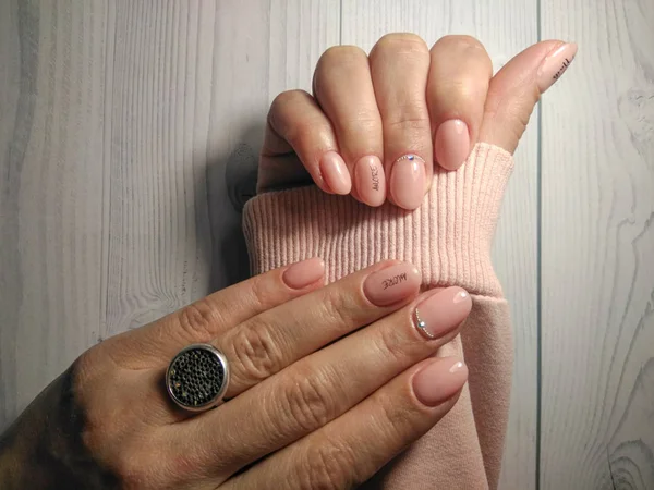 穿着粉红毛衣的女人手上漂亮的粉红指甲 漆面桃色带菱形石图案及题词 Amore — 图库照片