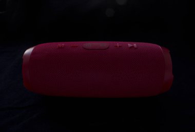 Kablosuz müzik hoparlörü. Siyah arkaplanda kırmızı bluetooth hoparlörü. Denetim ve ses düğmeleri.