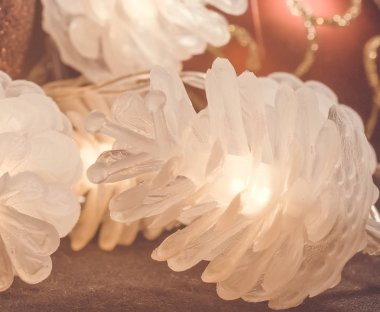 Arka planda Noel topları olan dekoratif parlak koniler. Noel ağacı için farklı renkte çelenk şeklinde Noel oyuncakları..