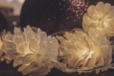 Arka planda Noel topları olan dekoratif parlak koniler. Noel ağacı için farklı renkte çelenk şeklinde Noel oyuncakları.