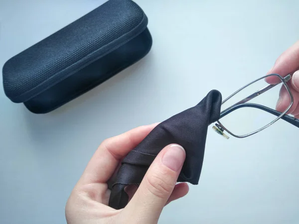 Black modern eyeglasses with case.Man wipes with a cloth the glass from contaminants.Cleaning glasses medical glasses.Glasses to restore vision.Glasses for the treatment of myopia and farsightedness.