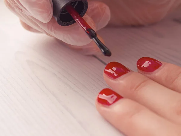 美甲师在病人的指甲上涂了油漆 美容师用刷子把你的指甲涂成红色 第一层 — 图库照片