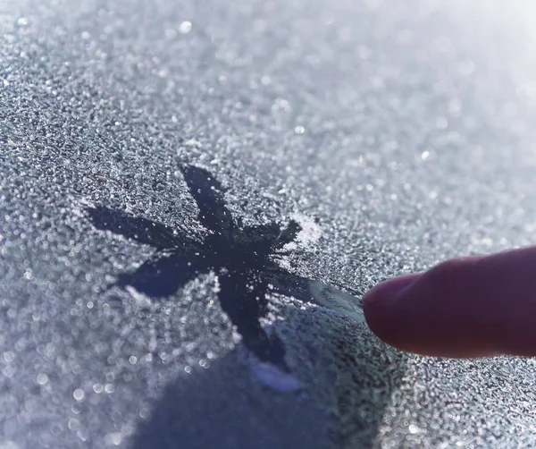 凍ったガラスに雪片を描く人 指が寒さの中で美しい雪の結晶を描いた — ストック写真