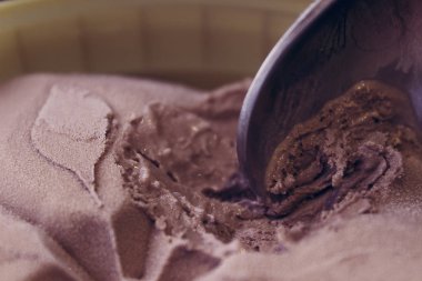 Bir kova çikolatalı dondurma ve kaşık. Kaşık, çikolatanın tadındaki dondurmayı aldı. Güzel dondurma deseni.