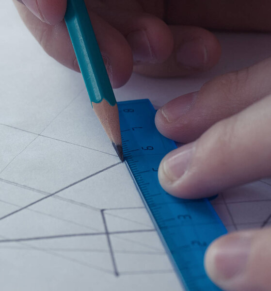 A man draws a scheme on white paper with a pencil using a ruler. Drawing project in pencil on a large sheet of close-up.
