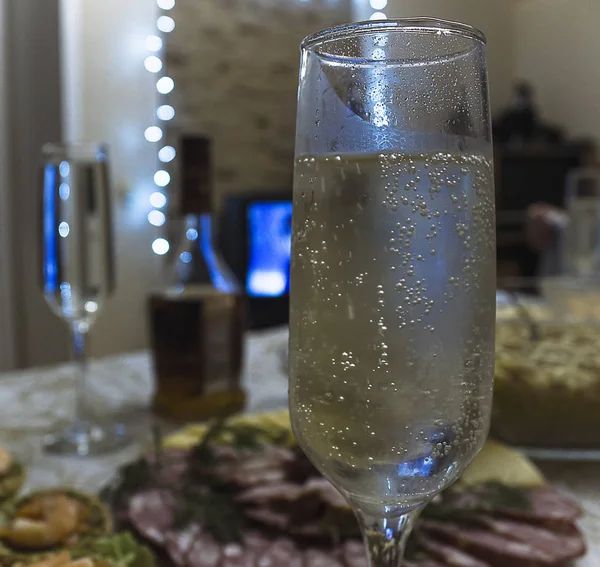 A glass of sparkling champagne on the background of a festive table. A couple of glasses of sparkling wine on a background of salads and shrimp tartlets.