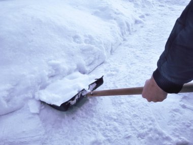 Winter snow shovel . A man shovels snow. Plastic black shovel with a wooden handle. A man cleans the snow in the yard.