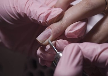 The manicurist cleans the cuticle of the nails with the device. Cuticle removal using a machine with a cutter. Professional manicure in the salon close-up.