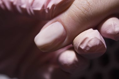 Pembe jel cilası tırnak tabağından aşağı akıyor. Manikürcü müşterinin tırnağına jöle cilası sürüyor. Güzellik salonunda profesyonel manikür..