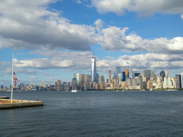 マンハッタンを背景にした川 ニューヨーク市中心部を背景に川 川の背景とニューヨークの中心にアメリカの旗を持つ旗竿 — ストック写真