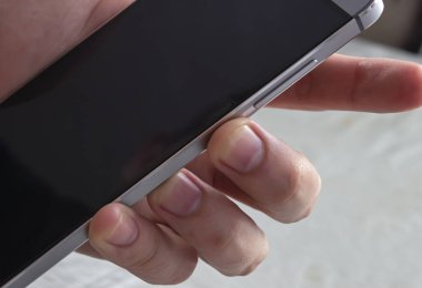 Bir kişi akıllı telefon tutuyor. Ses kontrolü ve kilit düğmeleri. Kilit düğmesine basan kişi.