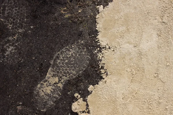 Footprints on the ground. Sandy boot prints on the ground next to a pile of sand.