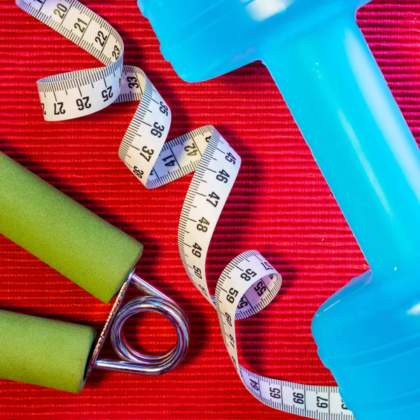 Lay Flat - Dumbbell, Measuring Tape, Hand Grip on red background