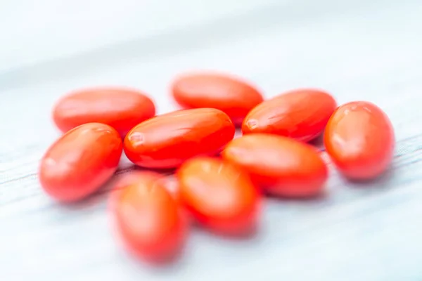 Comprimidos de vitaminas de cor vermelha em fundo de madeira. Foco suave. S — Fotografia de Stock