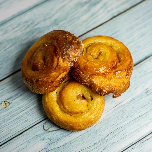 Homemade glazed puff pastry rolls on a  dark blue wooden backgro — Stockfoto