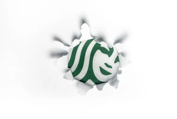 Kuala Lumpur, 2020 dolaylarında Starbucks logosu yırtılmış beyaz bir kağıdı delip geçiyor. Starbucks Corporation bir Amerikan kahve şirketi ve kahve zinciri..