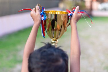 Elinde kupa tutan bir çocuk. O bir kazanan.