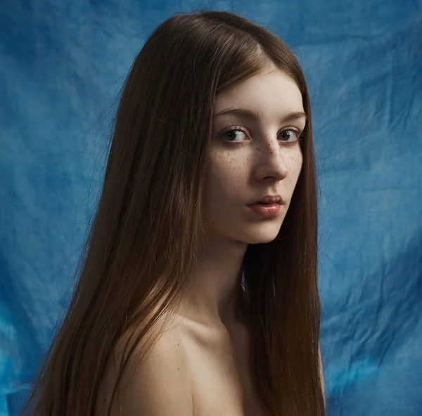 Tema da beleza: retrato de uma bela jovem com sardas em seu rosto e vestindo um vestido preto em um fundo azul em estúdio — Fotografia de Stock