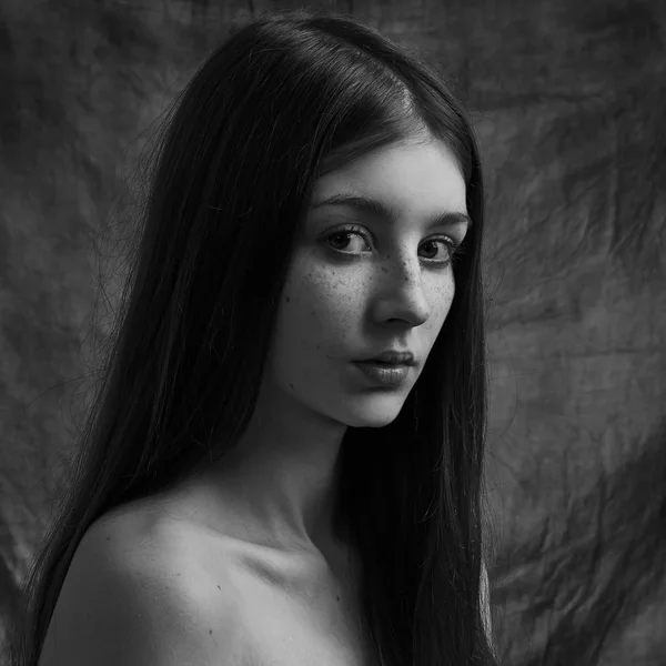 Dramático retrato preto e branco de uma bela menina solitária com sardas isoladas em um fundo escuro em estúdio tiro — Fotografia de Stock