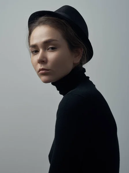 Çiller siyah bir balıkçı yaka ve beyaz bir arka plan Studio kafasına bir şapka ile güzel bir genç kızın dramatik portre — Stok fotoğraf