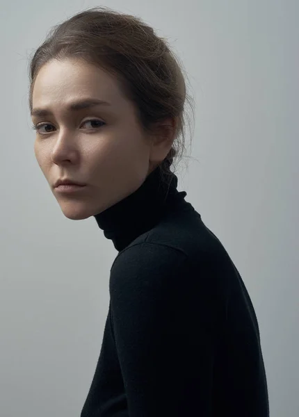 Portrait dramatique d'une jeune belle fille avec des taches de rousseur dans un col roulé noir sur fond blanc en studio — Photo