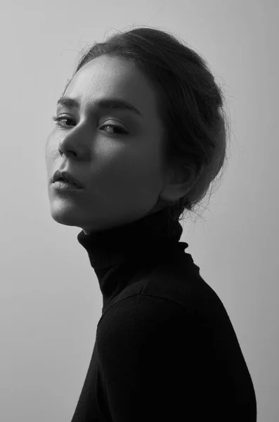 Dramático retrato en blanco y negro de una joven hermosa chica con pecas en un cuello alto negro sobre fondo blanco en el estudio —  Fotos de Stock