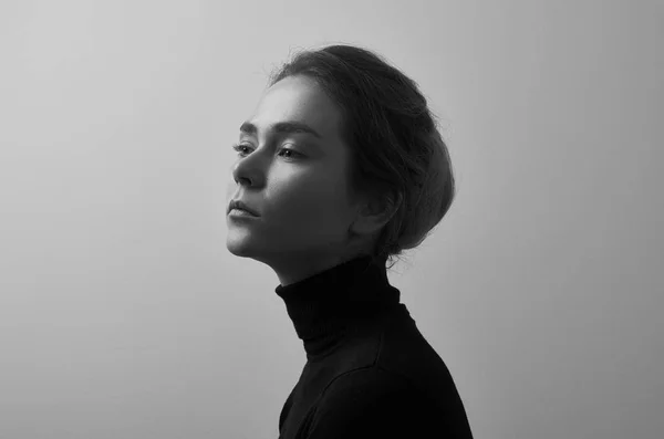 Dramatiska svartvita porträtt av ung vacker flicka med fräknar i en svart polotröja på vit bakgrund i studio — Stockfoto