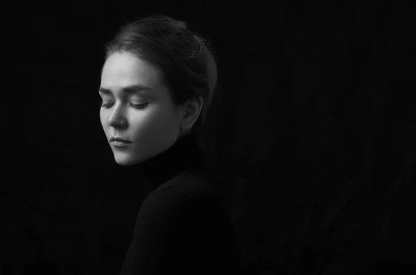 Dramatiska svartvita porträtt av ung vacker flicka med fräknar i en svart polotröja på svart bakgrund i studio — Stockfoto