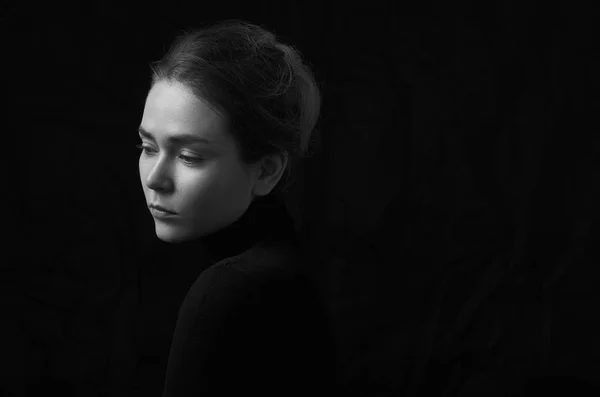 Dramatische zwart-wit portret van jong mooi meisje met sproeten in een zwarte coltrui op zwarte achtergrond in de studio — Stockfoto