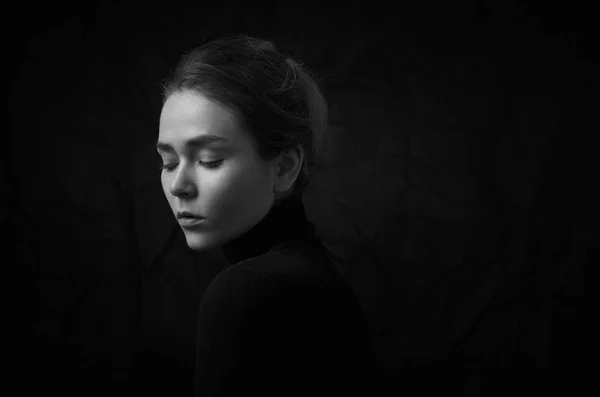 Dramatique portrait noir et blanc de jeune belle fille avec des taches de rousseur dans un col roulé noir sur fond noir en studio — Photo