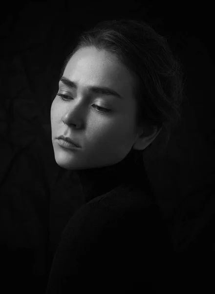 Dramatiska svartvita porträtt av ung vacker flicka med fräknar i en svart polotröja på svart bakgrund i studio — Stockfoto