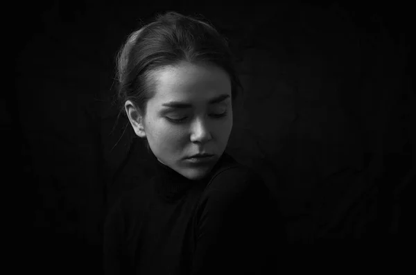 Dramático preto e branco retrato de jovem menina bonita com sardas em uma gola preta no fundo preto no estúdio — Fotografia de Stock