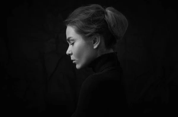 Драматический черно-белый портрет молодой красивой девушки с веснушками в черной водолазке на черном фоне в студии — стоковое фото